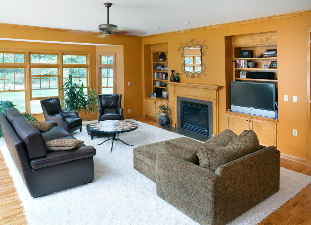 Пример оригинального дизайна: открытая гостиная комната среднего размера в классическом стиле с оранжевыми стенами, паркетным полом среднего тона, фасадом камина из камня, горизонтальным камином и отдельно стоящим телевизором