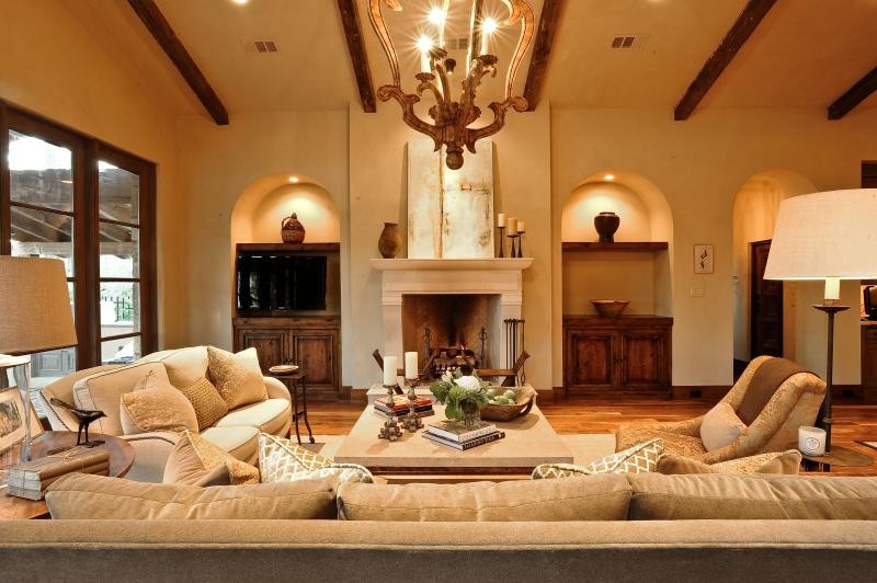 Photo of a medium sized mediterranean open plan games room in Other with beige walls, medium hardwood flooring, a standard fireplace, a stone fireplace surround and a built-in media unit.