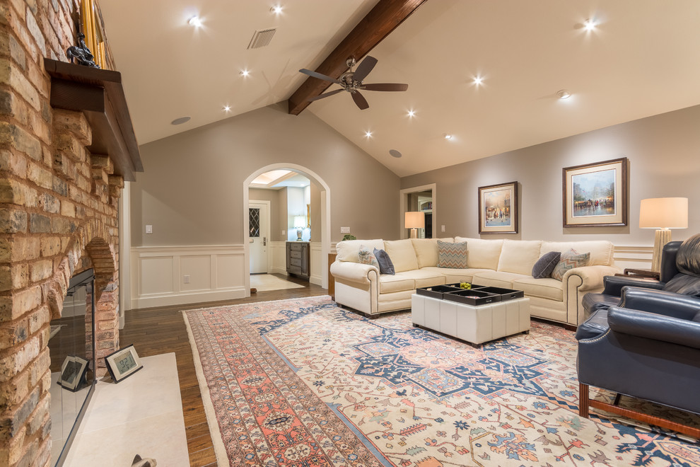 Ejemplo de sala de estar tradicional grande con paredes beige, suelo de madera en tonos medios, todas las chimeneas y marco de chimenea de ladrillo