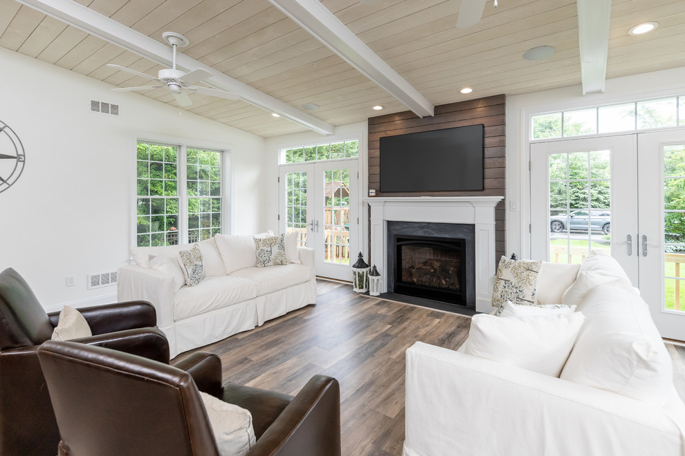 Imagen de sala de estar abierta contemporánea grande con paredes blancas, todas las chimeneas, marco de chimenea de madera, televisor colgado en la pared y suelo marrón