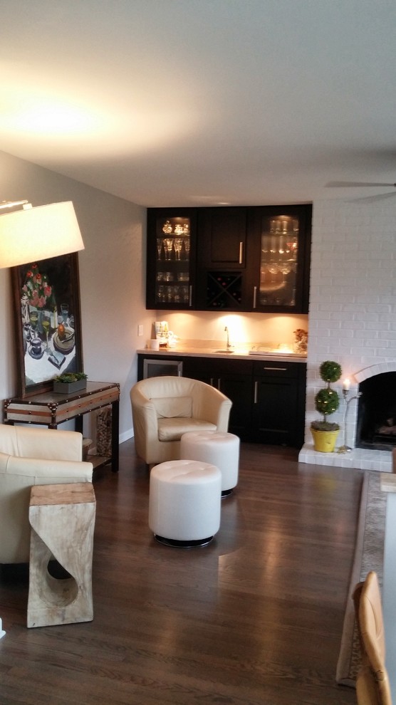 Foto de sala de estar con barra de bar bohemia de tamaño medio con suelo de madera en tonos medios, todas las chimeneas y marco de chimenea de ladrillo