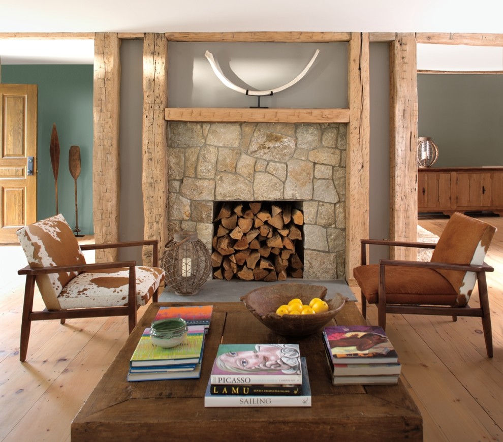 Rustikales Wohnzimmer mit brauner Wandfarbe, dunklem Holzboden, Kamin, Kaminumrandung aus Stein und braunem Boden in New York