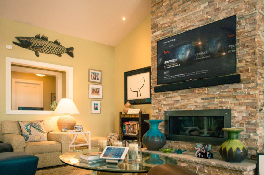 Foto de sala de estar abierta marinera grande con paredes amarillas, chimenea lineal, marco de chimenea de metal, televisor colgado en la pared y suelo de madera clara
