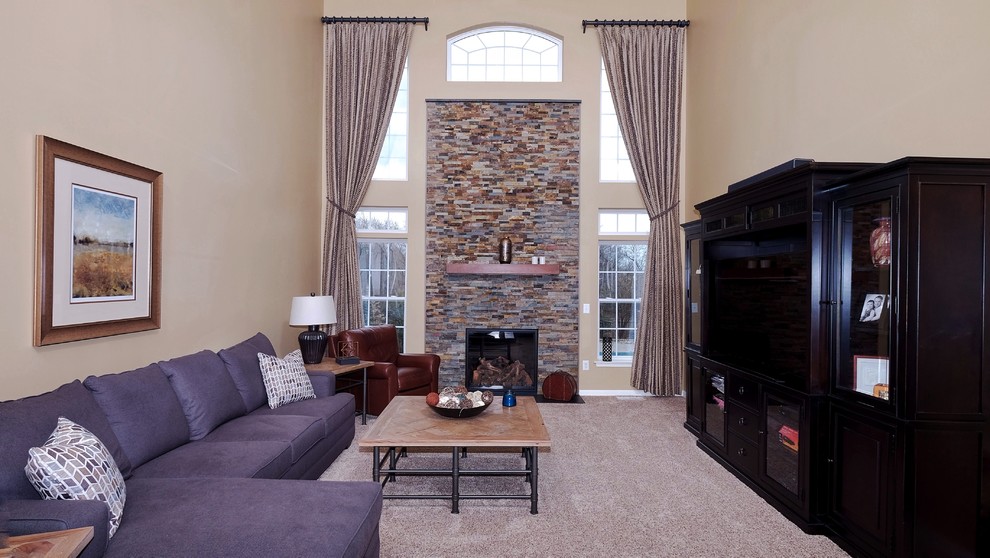 На фото: большая открытая гостиная комната в стиле неоклассика (современная классика) с желтыми стенами, ковровым покрытием, стандартным камином и фасадом камина из камня с