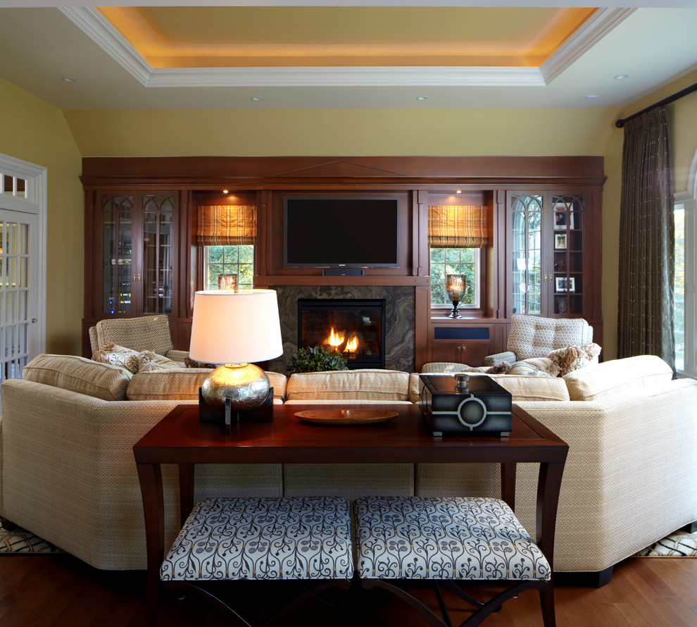 Mittelgroßes, Offenes Klassisches Wohnzimmer mit beiger Wandfarbe, braunem Holzboden, Kamin, Kaminumrandung aus Stein und TV-Wand in New York