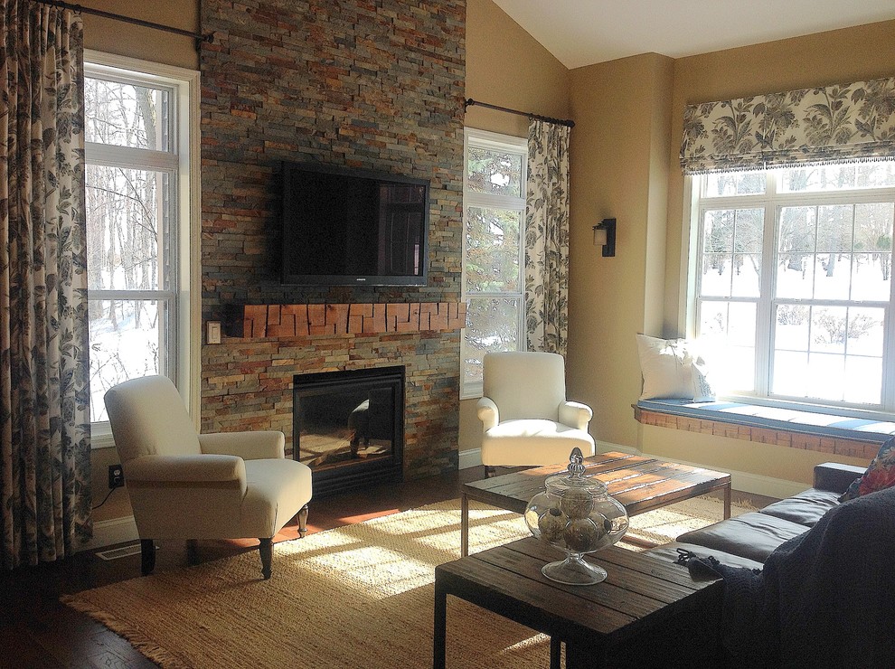 This is an example of a medium sized rustic open plan games room in Detroit with beige walls, medium hardwood flooring, a standard fireplace, a wooden fireplace surround and a wall mounted tv.