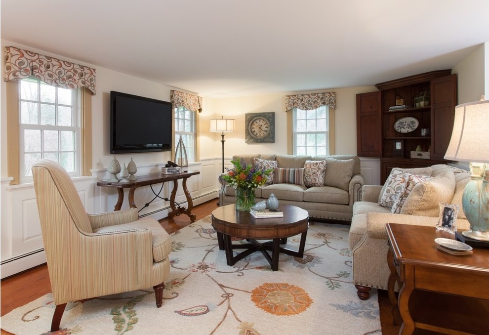 Ejemplo de sala de estar cerrada tradicional grande sin chimenea con paredes beige, suelo de madera en tonos medios, televisor colgado en la pared y suelo marrón