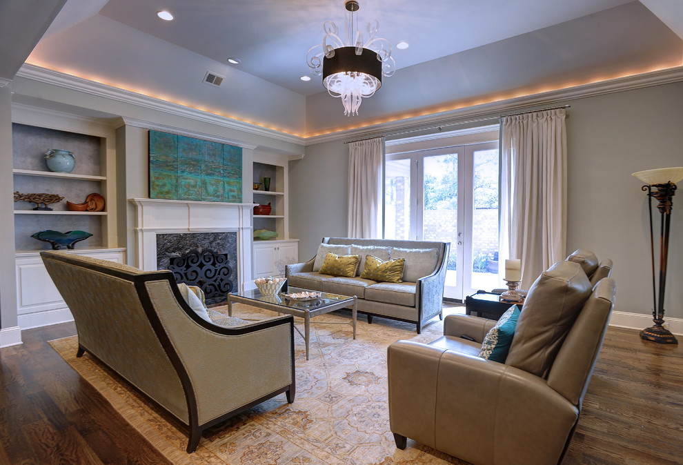 Foto de sala de estar abierta clásica renovada grande con paredes grises, suelo de madera en tonos medios, todas las chimeneas, marco de chimenea de piedra y televisor retractable