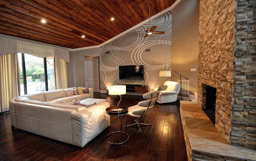 Mittelgroßes, Offenes Modernes Wohnzimmer mit grauer Wandfarbe, dunklem Holzboden, Kamin, Kaminumrandung aus Stein, TV-Wand und grauem Boden in Houston