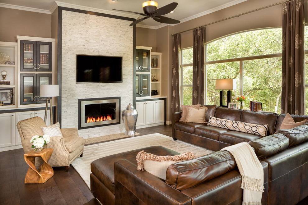 Modelo de sala de estar tradicional renovada con marco de chimenea de piedra, paredes marrones, suelo de madera oscura y chimenea lineal