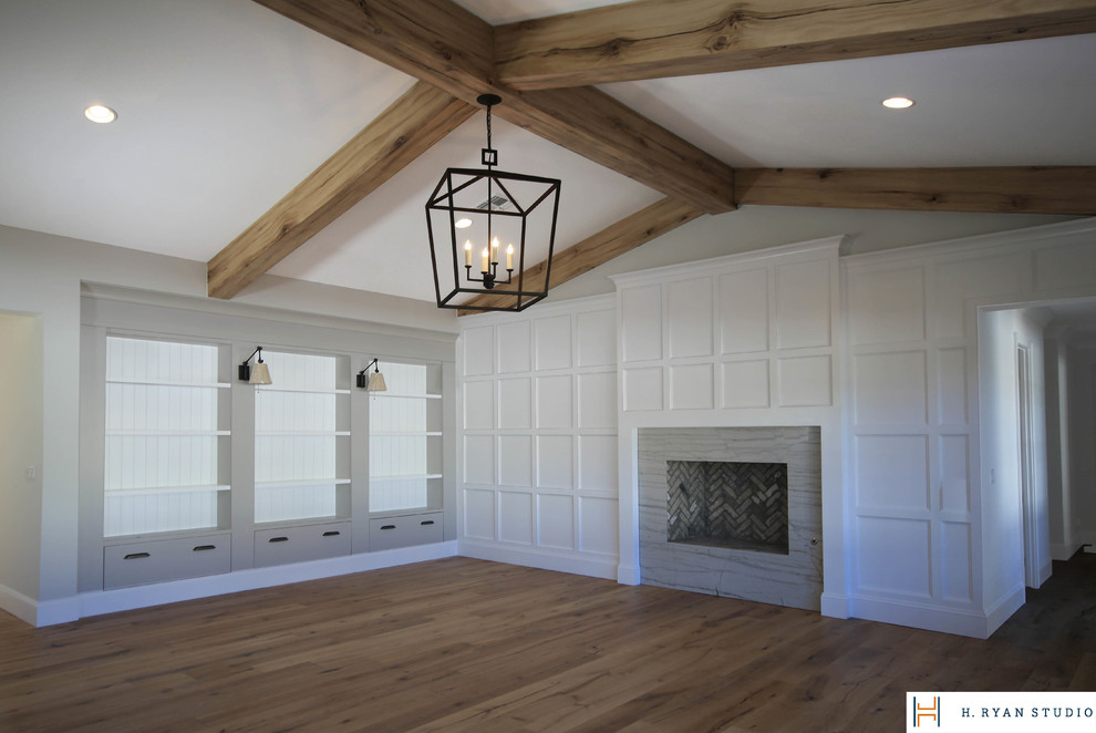 Diseño de sala de estar abierta tradicional renovada con paredes blancas, suelo de madera en tonos medios, todas las chimeneas y marco de chimenea de piedra