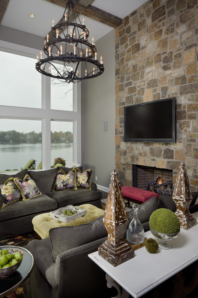Idée de décoration pour une salle de séjour tradition avec un mur gris, une cheminée standard, un manteau de cheminée en pierre et un téléviseur fixé au mur.