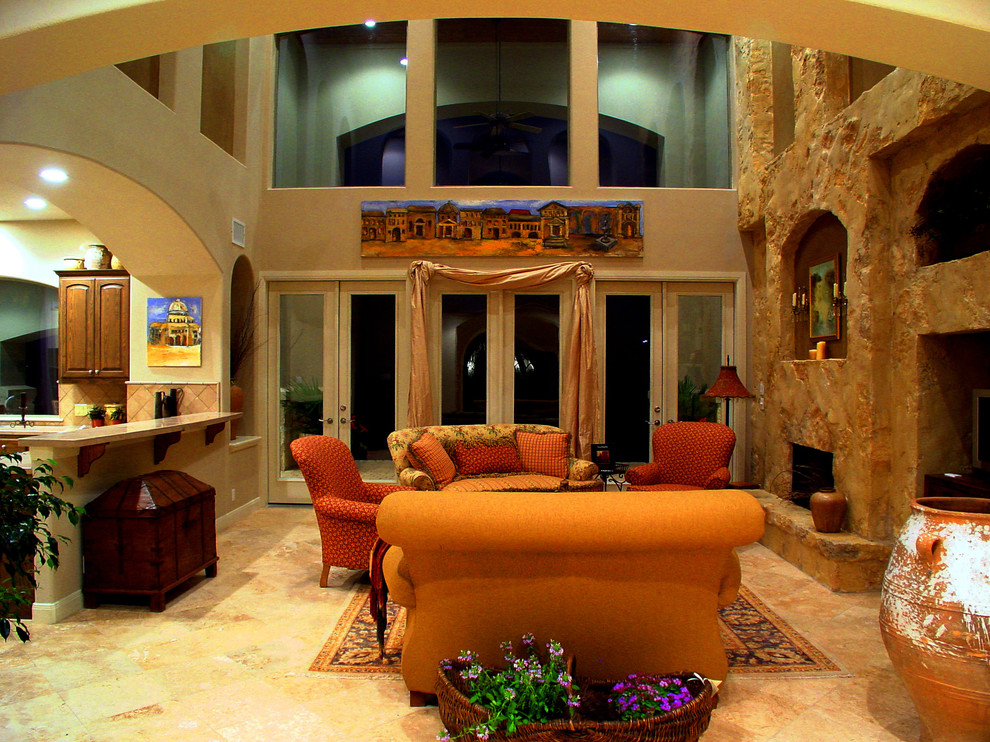 Example of a large tuscan open concept travertine floor family room design in Austin with beige walls and a standard fireplace