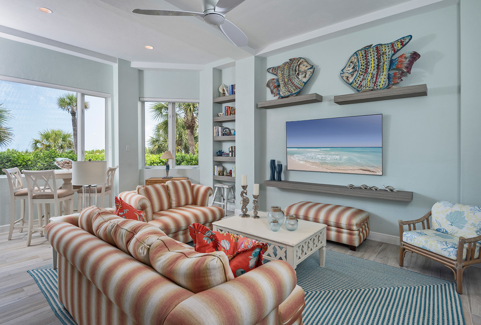 Ejemplo de sala de estar abierta marinera con paredes azules, televisor colgado en la pared y suelo gris