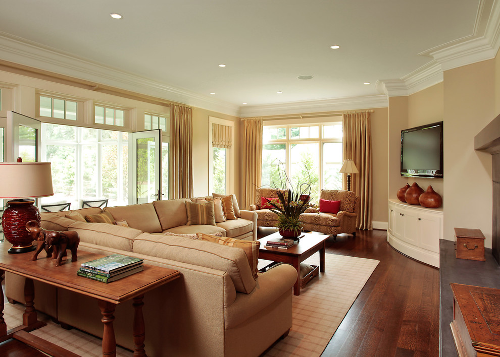 Пример оригинального дизайна: гостиная комната в классическом стиле с бежевыми стенами, паркетным полом среднего тона, телевизором в углу и ковром на полу