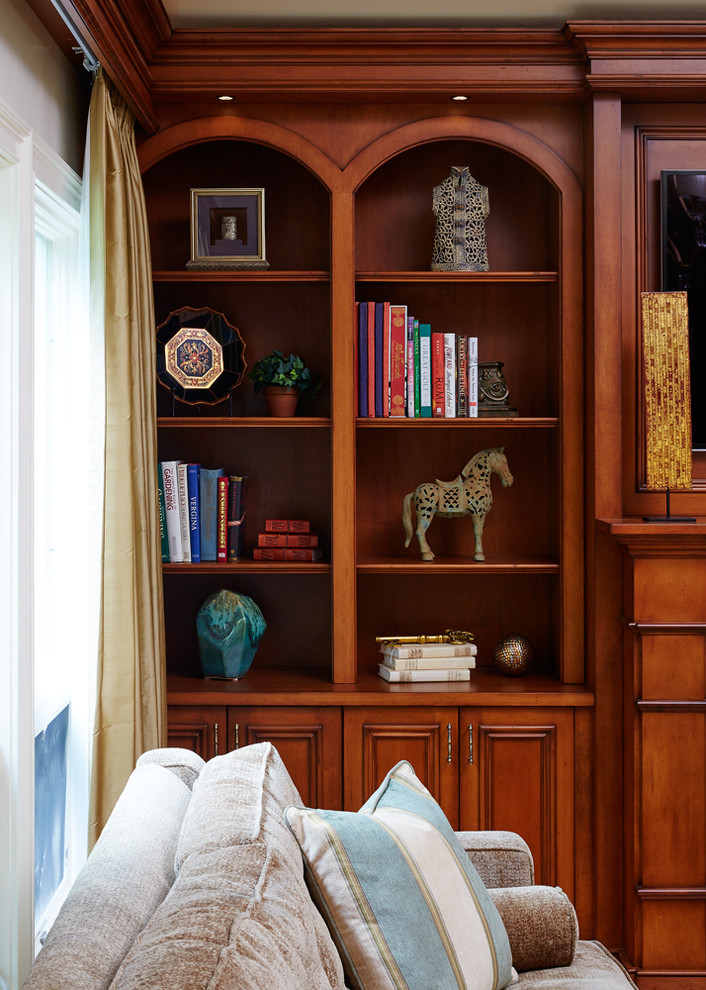 На фото: гостиная комната среднего размера в стиле неоклассика (современная классика) с с книжными шкафами и полками, стандартным камином и фасадом камина из дерева с