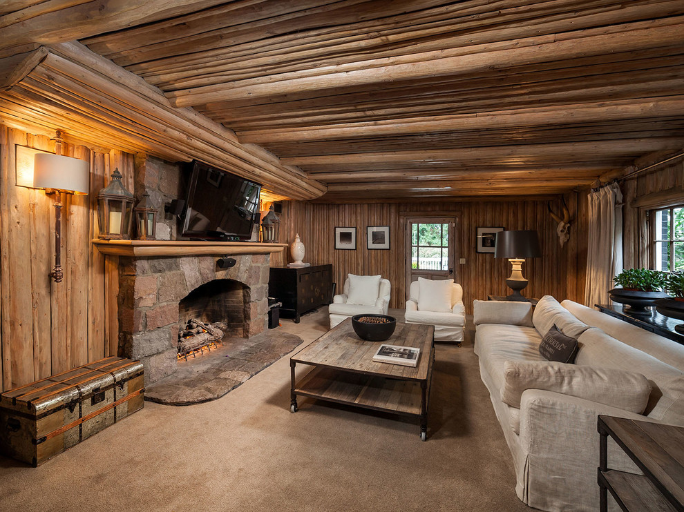 Cette image montre une salle de séjour chalet fermée avec moquette, une cheminée standard, un manteau de cheminée en pierre et un téléviseur fixé au mur.