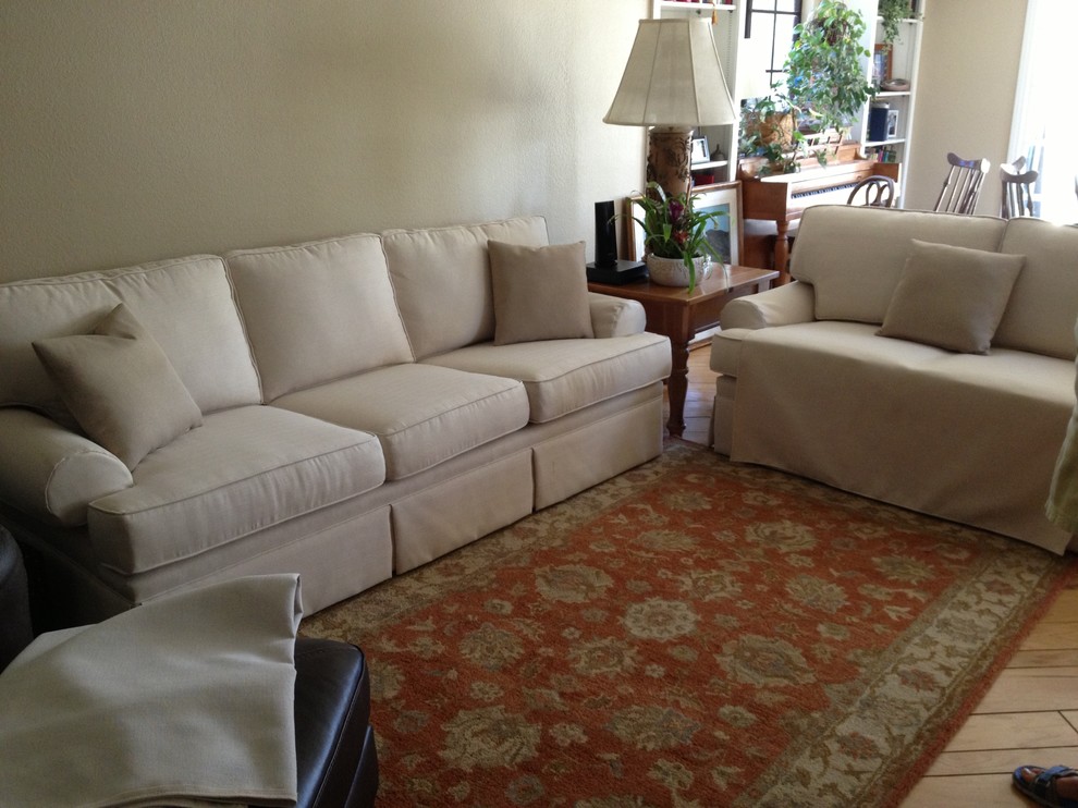 Imagen de sala de estar abierta tradicional de tamaño medio con paredes beige, suelo de madera clara y pared multimedia