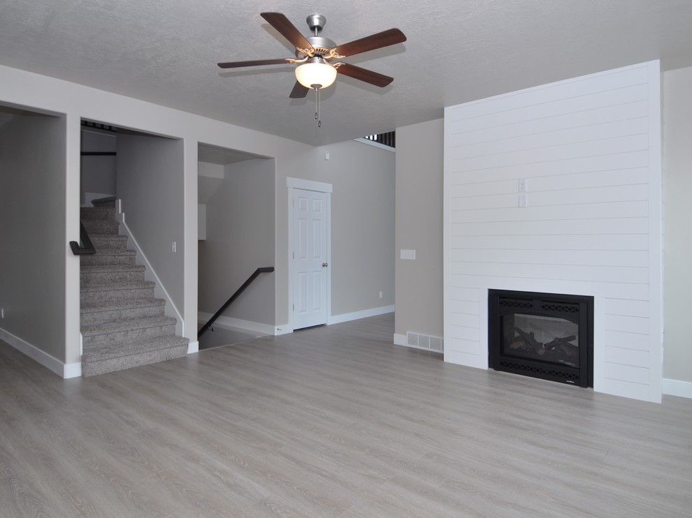 Foto de sala de estar cerrada de estilo americano de tamaño medio con paredes grises, suelo laminado y chimenea de doble cara