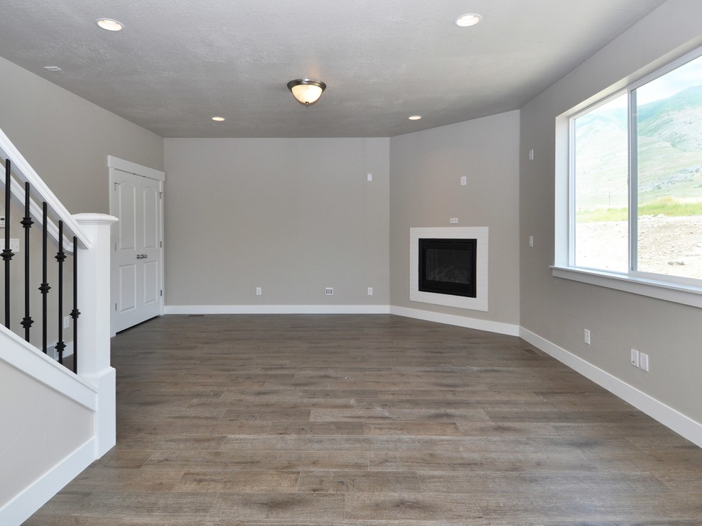 Ejemplo de sala de estar abierta de estilo americano de tamaño medio con paredes grises, suelo laminado, todas las chimeneas y suelo marrón