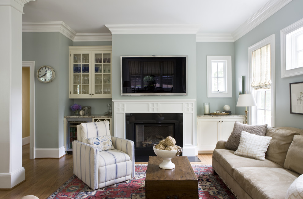 Example of a classic medium tone wood floor family room design in DC Metro with gray walls, a standard fireplace and a wall-mounted tv
