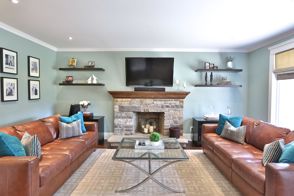 На фото: гостиная комната в классическом стиле с синими стенами, стандартным камином, фасадом камина из камня и телевизором на стене с