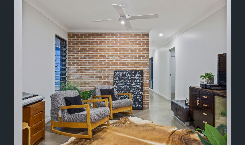 Cette image montre une salle de séjour design de taille moyenne et ouverte avec un mur blanc, sol en béton ciré, un sol gris et un mur en parement de brique.