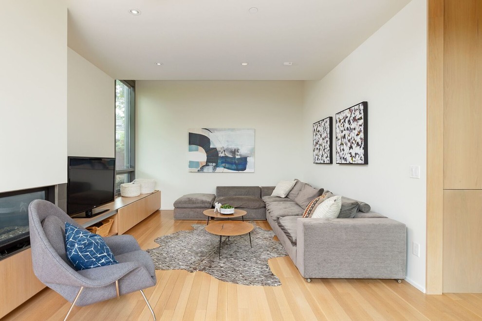 Foto de sala de estar actual con paredes blancas, suelo de madera en tonos medios, chimenea lineal, televisor independiente y suelo marrón