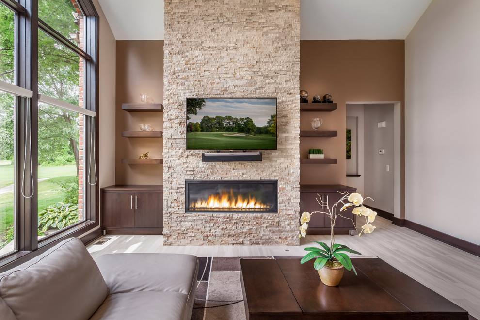 Inspiration for a mid-sized modern open concept porcelain tile and beige floor family room remodel in Detroit with brown walls, a standard fireplace, a stone fireplace and a wall-mounted tv