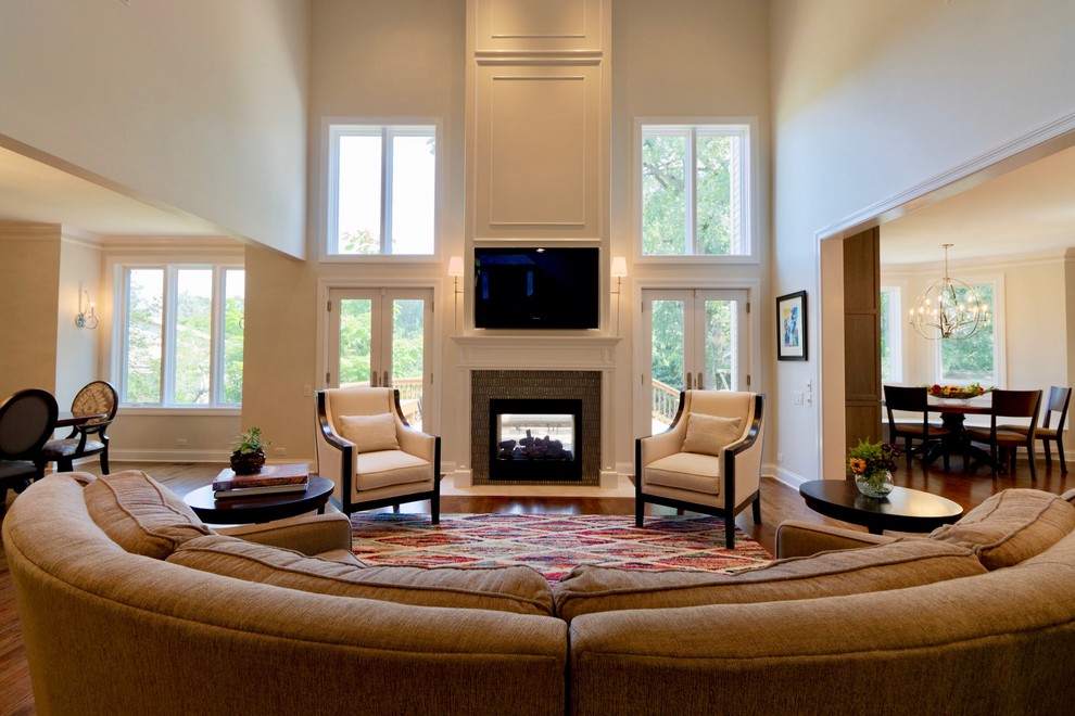Foto de sala de estar abierta clásica renovada grande con suelo de madera en tonos medios, chimenea de doble cara, marco de chimenea de madera y televisor colgado en la pared