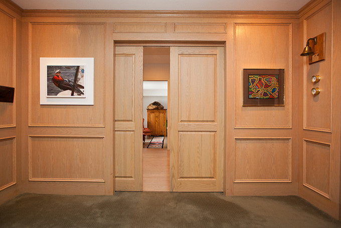 На фото: открытая гостиная комната среднего размера в современном стиле с ковровым покрытием, с книжными шкафами и полками, бежевыми стенами, телевизором на стене, серым полом, многоуровневым потолком и деревянными стенами с
