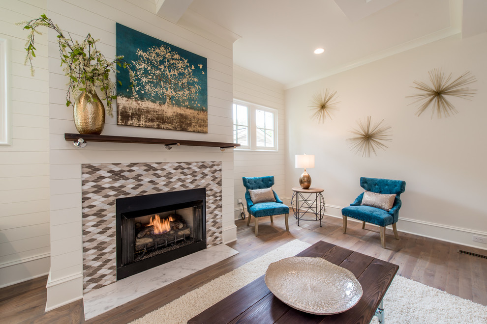 Cette image montre une grande salle de séjour traditionnelle ouverte avec un mur blanc, un sol en bois brun, une cheminée standard, un manteau de cheminée en carrelage et un sol marron.