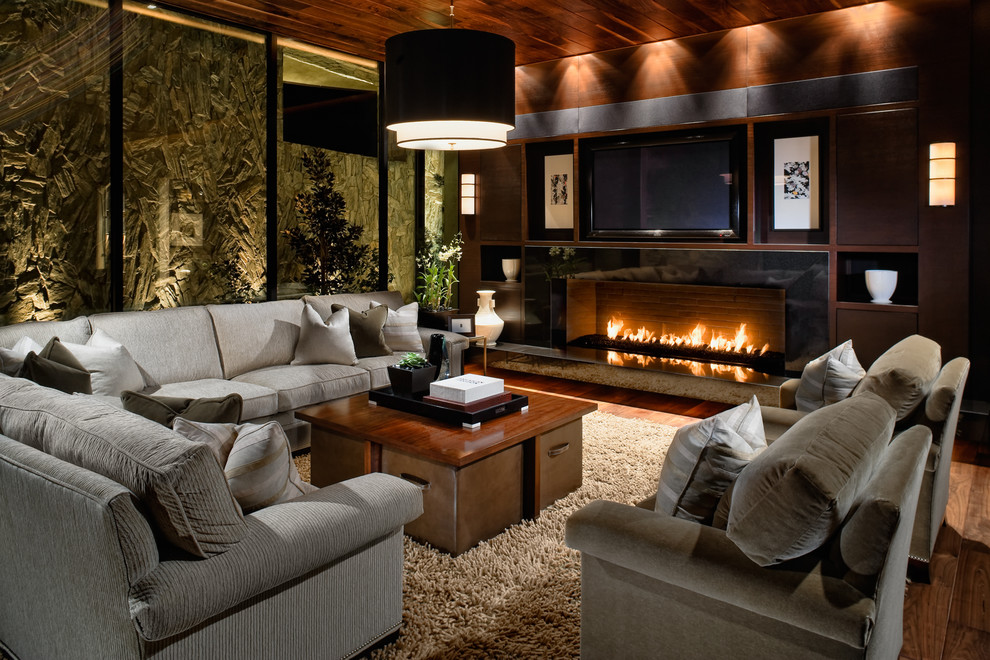 Contemporary games room in Las Vegas with dark hardwood flooring, a ribbon fireplace and a wall mounted tv.