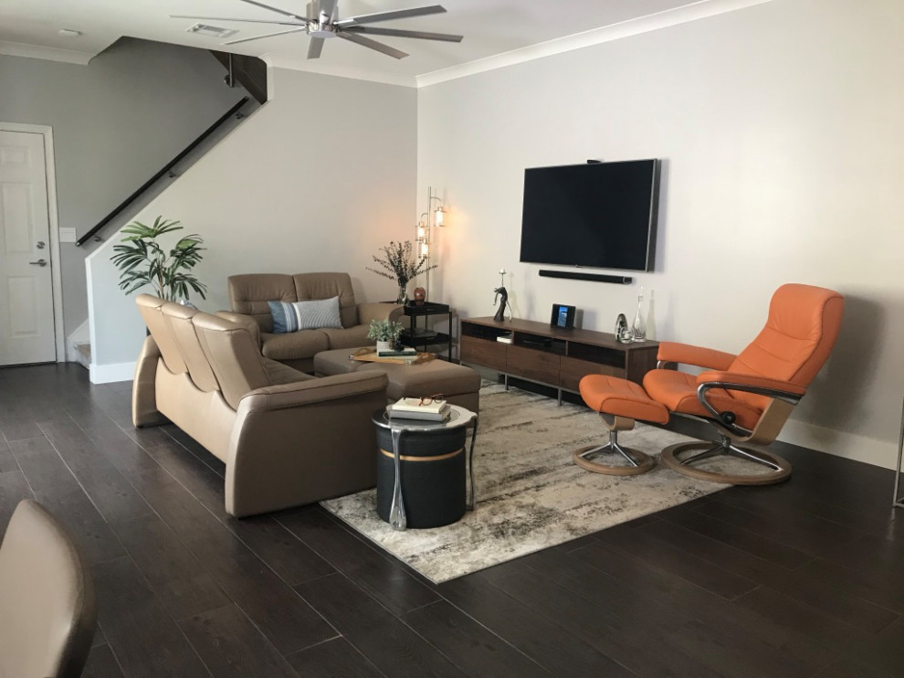 Ejemplo de sala de estar abierta actual grande con paredes grises, suelo de baldosas de porcelana, televisor colgado en la pared y suelo marrón