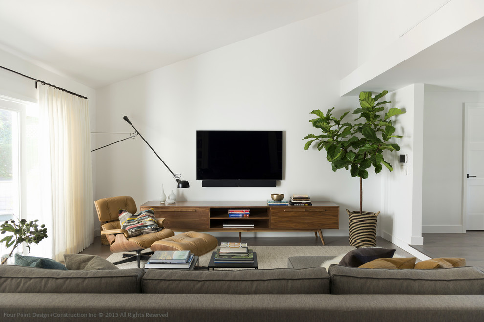 Diseño de sala de estar abierta actual grande sin chimenea con paredes blancas, suelo de madera en tonos medios y televisor colgado en la pared
