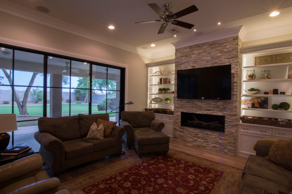 Diseño de sala de estar abierta de estilo de casa de campo con suelo de madera en tonos medios, chimenea lineal, marco de chimenea de piedra, pared multimedia y paredes beige