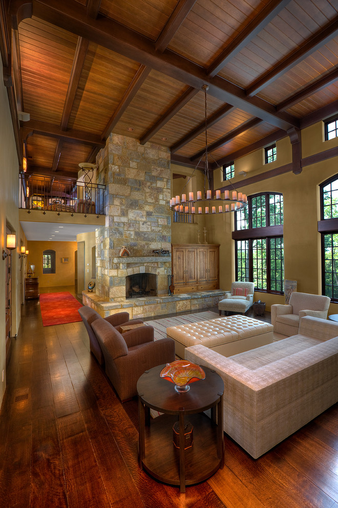 Offenes Mediterranes Wohnzimmer mit beiger Wandfarbe, dunklem Holzboden, Kamin und Kaminumrandung aus Stein in Cincinnati