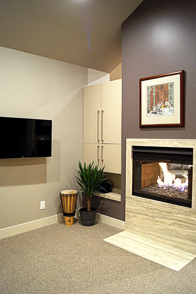 Imagen de sala de estar cerrada actual con paredes grises, moqueta, chimenea de doble cara y marco de chimenea de piedra