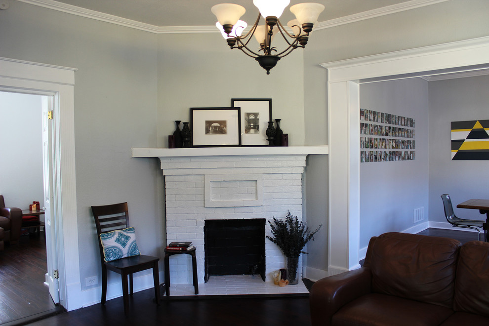 Mittelgroßes, Fernseherloses, Abgetrenntes Rustikales Wohnzimmer mit grauer Wandfarbe, dunklem Holzboden, Kamin und Kaminumrandung aus Backstein in Dallas
