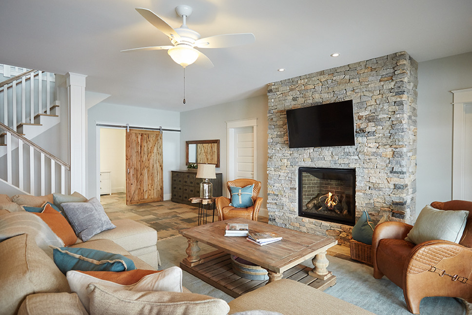 Inspiration for a mid-sized coastal open concept slate floor family room remodel in Grand Rapids with gray walls, a standard fireplace, a stone fireplace and a wall-mounted tv