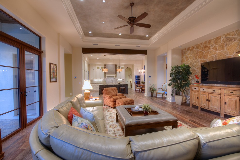 Idee per un soggiorno chic aperto con pareti beige, pavimento in legno massello medio, TV a parete e tappeto