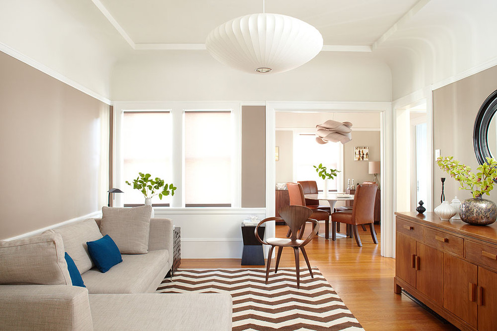 Imagen de sala de estar cerrada contemporánea de tamaño medio sin chimenea con paredes beige y suelo de madera en tonos medios