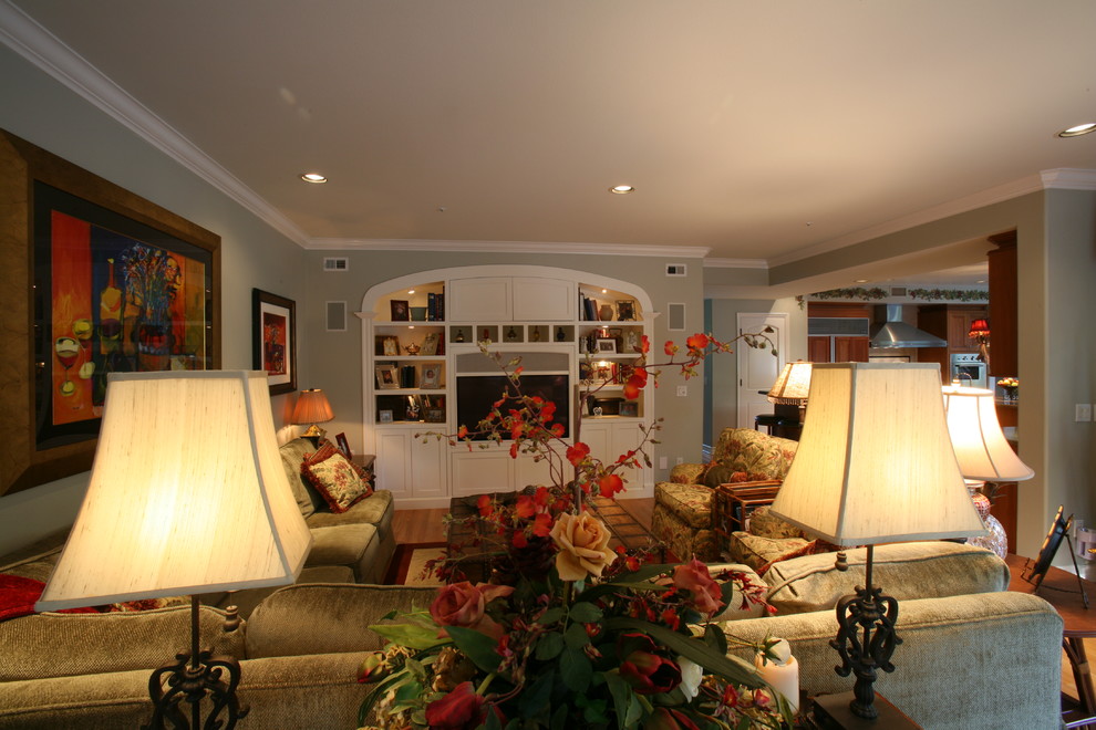 Cette image montre une grande salle de séjour traditionnelle ouverte avec un mur vert, un sol en bois brun et un téléviseur encastré.