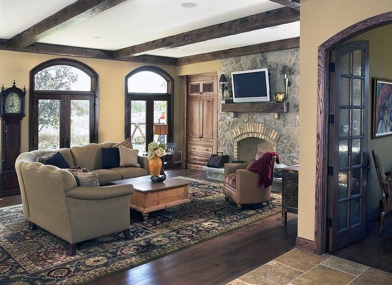 Inspiration for a large mediterranean open concept dark wood floor family room remodel in Chicago with beige walls, a standard fireplace, a stone fireplace and a wall-mounted tv