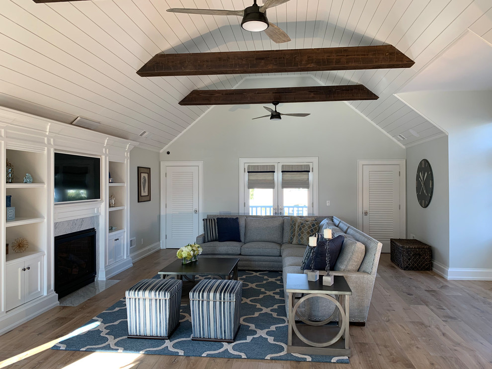 Design ideas for a medium sized coastal mezzanine games room in Other with blue walls, medium hardwood flooring, a standard fireplace, a built-in media unit and brown floors.