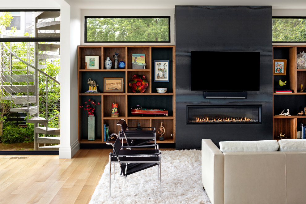 Imagen de sala de estar abierta moderna extra grande con paredes blancas, suelo de madera clara, chimenea lineal, televisor colgado en la pared, suelo marrón y marco de chimenea de metal
