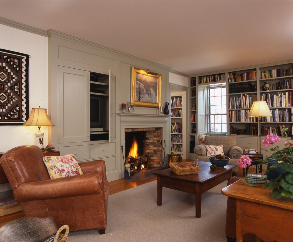 Aménagement d'une salle de séjour de taille moyenne et ouverte avec une bibliothèque ou un coin lecture, un mur blanc, un sol en bois brun, une cheminée standard, un manteau de cheminée en brique et un téléviseur encastré.