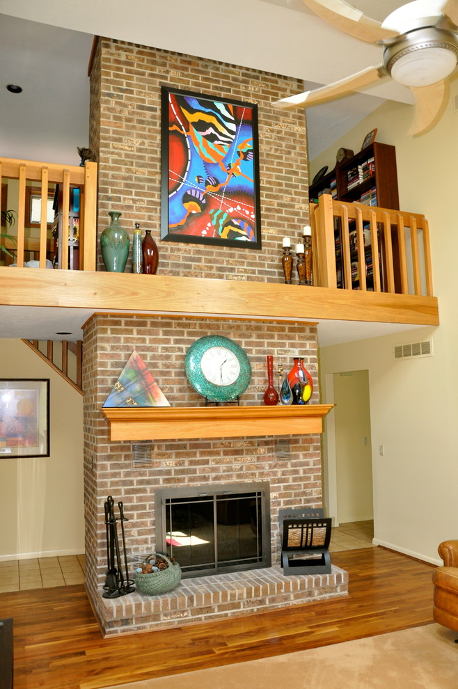 Exemple d'une salle de séjour mansardée ou avec mezzanine chic de taille moyenne avec un mur beige, un sol en bois brun, une cheminée standard, un manteau de cheminée en brique et un téléviseur indépendant.