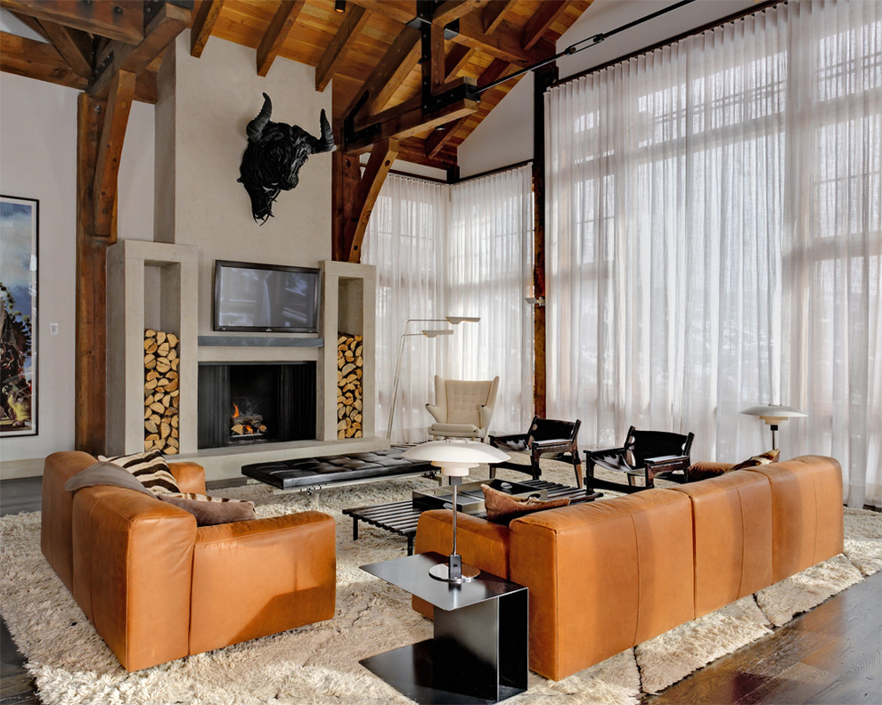 Imagen de sala de estar abierta rural con paredes beige, suelo de madera oscura, todas las chimeneas y televisor colgado en la pared