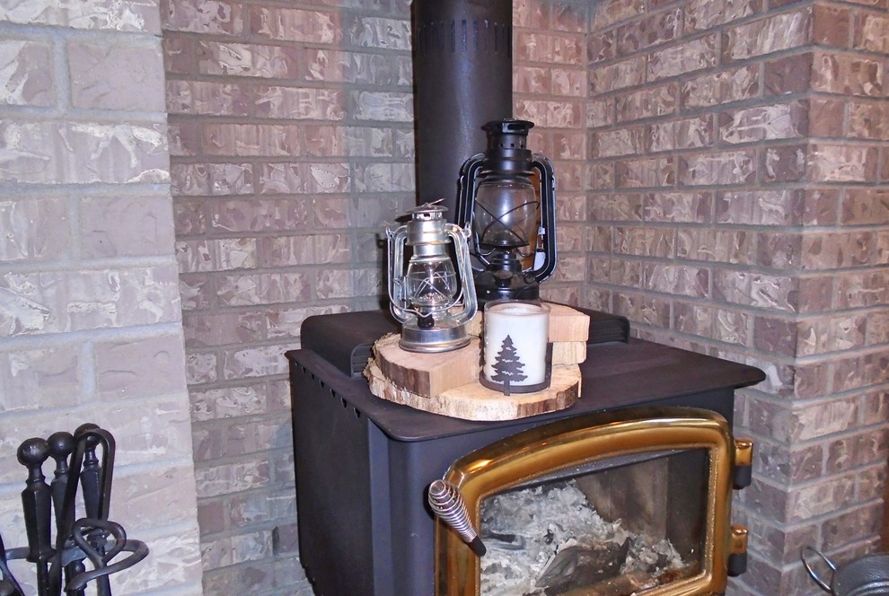 Foto de sala de estar abierta rústica de tamaño medio con estufa de leña y marco de chimenea de ladrillo